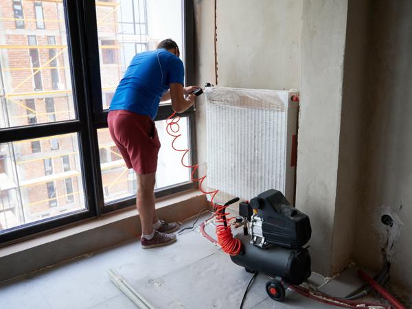 Plumber using air compressor to test heating system pipes